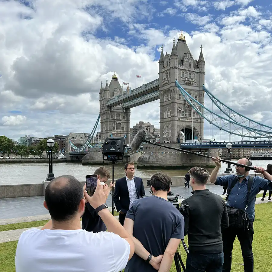 Video Production London photo features a number of film crew interviewing a man in Potter's Field Park overlooking Tower Bridge on the Thames.